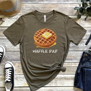 K&ouml;nnte beinhalten: Ein gr&uuml;nes T-Shirt mit einer Waffelgrafik und dem Aufdruck "Waffle Dad".