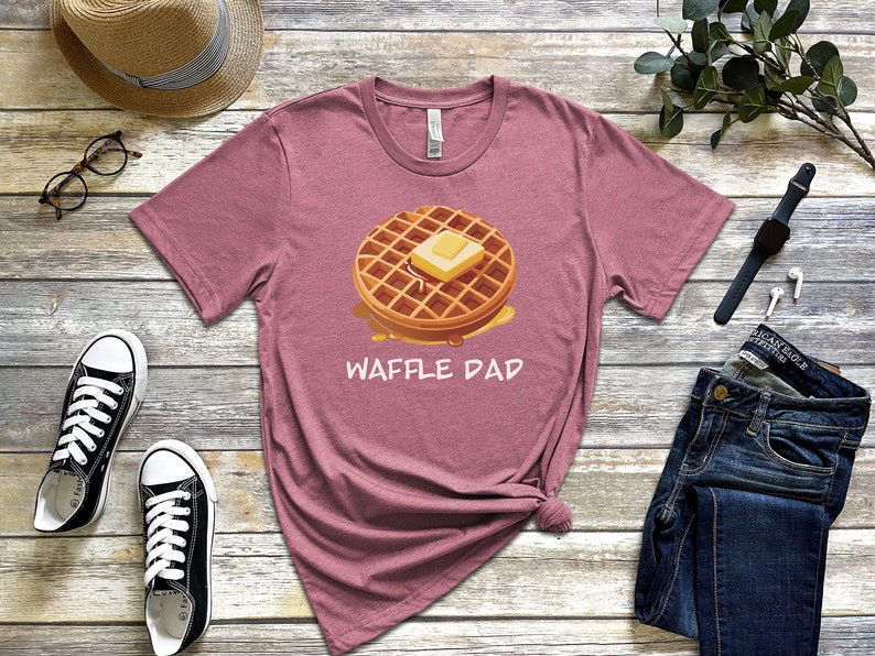 K&ouml;nnte beinhalten: Ein heidefarbenes T-Shirt mit einem Aufdruck einer Waffel mit Butter und Sirup. Der Text "Waffle Dad" ist unter der Waffel aufgedruckt.