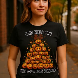 May include: Black t-shirt with the text "WHO NEEDS PINE WHEN YOU'VE GOT PUMPKIN" and a graphic of a pumpkin-shaped tree. The tree is made of orange pumpkins with smiling faces. The shirt is worn by a person.
