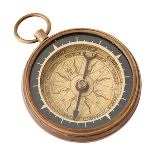 May include: A round brass compass featuring a vintage-style face with a beige background, black cardinal directions, and decorative sunburst patterns. The device includes a black needle and a circular brass ring attached to the top for hanging.
