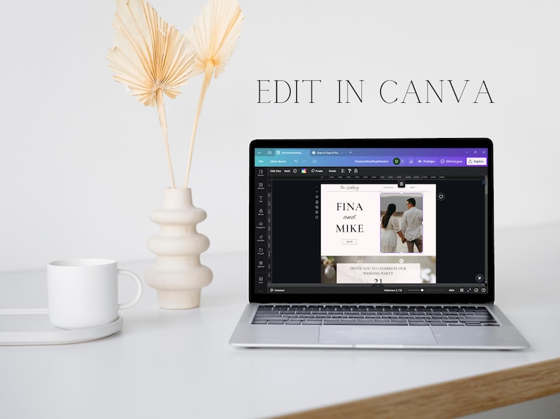 May include: A laptop displaying a wedding invitation design with the text "FINA and MIKE" and "INVITE YOU TO CELEBRATE OUR WEDDING PARTY 21". The screen is open on a white desk next to a white mug, a decorative vase, and dried palm leaves. The text "EDIT IN CANVA" is above the laptop.