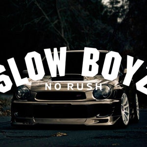 Puede incluir: Un coche negro con las palabras "SLOW BOYZ NO RUSH" en letras blancas en la parte delantera.