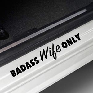 Op de afbeelding: Een witte autodeur met een zwarte vinyl sticker met de tekst "BADASS Wife ONLY".