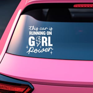 Op de afbeelding: Witte vinyl auto sticker met de tekst "This car is running on GIRL power" met een bliksem in het woord "GIRL" en sterren aan weerszijden van het woord "power".