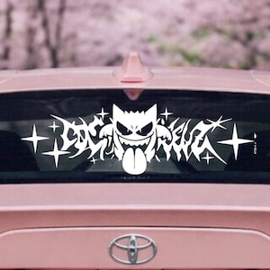 Op de afbeelding: Witte vinyl auto sticker met een cartoon spook karakter met een lange tong en de tekst "LOSER REBEL" in een gestileerd lettertype. De sticker bevat ster- en vlam-achtige accenten, ontworpen voor autoruiten.