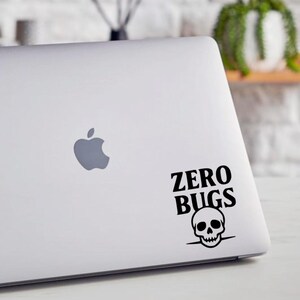 Op de afbeelding: Een witte laptop met een zwarte sticker met de tekst "ZERO BUGS" boven een schedel. De laptop heeft het Apple-logo. Het ontwerp is humoristisch.