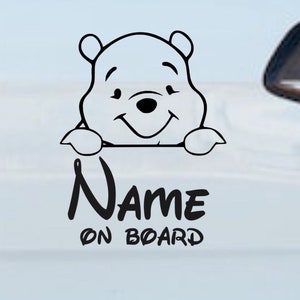 Könnte beinhalten: Schwarzweißes Winnie Puuh-Cartoon-Figure, die über ein Schild mit der Aufschrift "NAME ON BOARD" schaut.