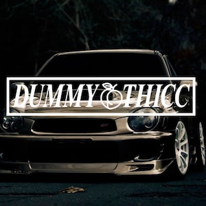 May include: A silver Subaru Impreza with a black and white sticker that says "DUMMY & THICC" on the front bumper.