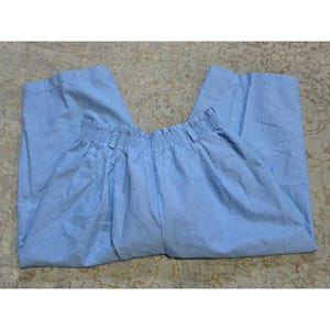 May include: Light blue trousers featuring a high-waisted design with a gathered, elasticized paperbag-style waistband. These pants have a relaxed fit through the legs, side pockets, and a straight hemline, crafted from a solid-colored fabric.