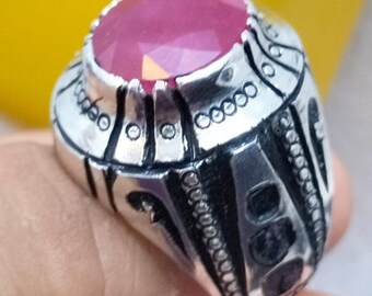 May include: A silver ring with an ornate design and a large, faceted, pink gemstone.