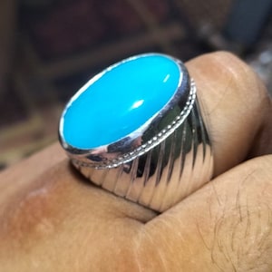 Könnte beinhalten: Ein silberner Ring mit einem großen, ovalen, hellblauen Edelstein.