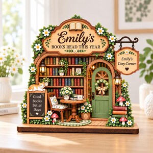 May include: A wooden bookshelf diorama featuring the text Emily's Books Read This Year and Emily's Cozy Corner. It includes miniature books, a green door, a chair, a table, a cat, daisies, mushrooms, and two small lanterns on a base.