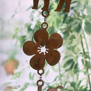 May include: A metal wind chime featuring a brown flower, a bird, and two deer silhouettes. The wind chime is hanging from a chain.