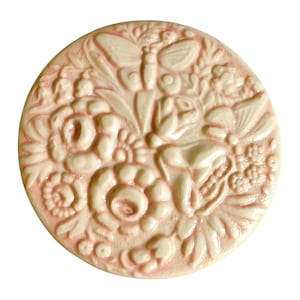 May include: A white ceramic tile with a raised design of pink flowers, butterflies, and leaves. The tile has a glossy finish.