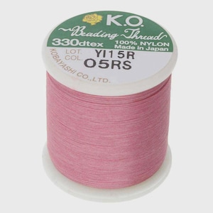 May include: A spool of pink K.O. Beading Thread made of 100% nylon. The white label on top features green text reading K.O. Beading Thread, 330dtex, 100% NYLON, Made in Japan, LOT YI15R, and COL 05RS, with a small yellow rose icon at the top.