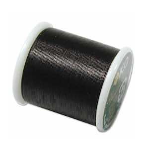 May include: A spool of black sewing thread wound tightly around a white plastic cylinder. The spool features white circular end caps with the letters KQ printed in white on the right side, along with a small green circular logo.