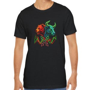 May include: Black t-shirt featuring a graphic of a bear and a bull, representing market trends. The bear is red, the bull is green, and both are set against a backdrop of stock market charts and arrows. A bold design for finance enthusiasts.