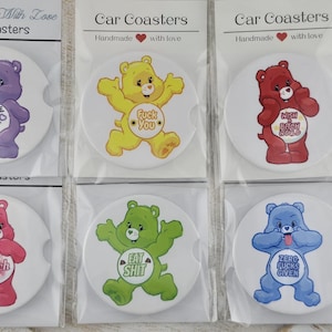 May include: Set of six car coasters featuring cartoon bears in various colors, each with a different offensive phrase. The coasters are packaged in clear plastic and are labeled "Handmade With Love" and "Car Coasters".