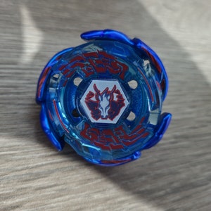 May include: A blue and red spinning top toy with a central emblem. The toy has a circular design with red accents and a central emblem featuring a stylized animal. The toy is designed for spinning and battling.