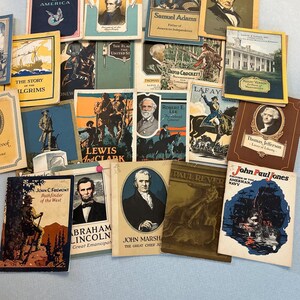 May include: A collection of vintage books with historical themes. Titles include "Patriotic Songs of America," "Andrew Jackson," "Samuel Adams," and "Daniel Webster." The covers feature illustrations and portraits, with a variety of colors and designs.