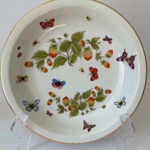 May include: A white ceramic pie plate with a gold rim features a design of strawberries and butterflies. The strawberries are red and green, and the butterflies are various colors, including blue, purple, and orange.