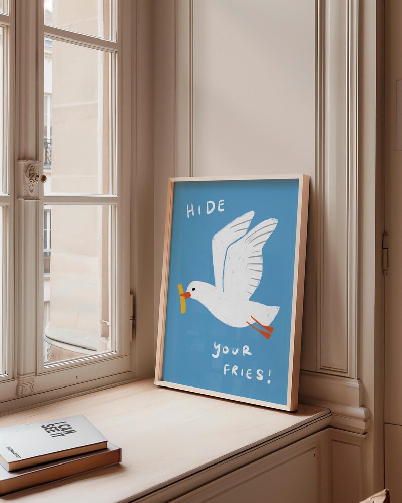 A cheeky seagull eyes a pile of fries in this vibrant, maximalist illustration, bursting with bold colors and playful text warning to protect your snacks. Perfect for adding a humorous coastal vibe to kitchens, beach house nooks, or sunny living spaces. Quirky vacation art, funny home accent, dopamine decor gift, coastal wall hanging, playful beachy print. Ideal for fry-loving friends or anyone craving a lighthearted, maximalist touch to their decor. Frame it for a pop of joy in any room.