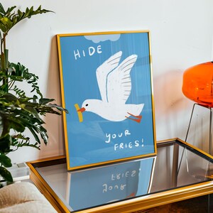 A cheeky seagull eyes a pile of fries in this vibrant, maximalist illustration, bursting with bold colors and playful text warning to protect your snacks. Perfect for adding a humorous coastal vibe to kitchens, beach house nooks, or sunny living spaces. Quirky vacation art, funny home accent, dopamine decor gift, coastal wall hanging, playful beachy print. Ideal for fry-loving friends or anyone craving a lighthearted, maximalist touch to their decor. Frame it for a pop of joy in any room.