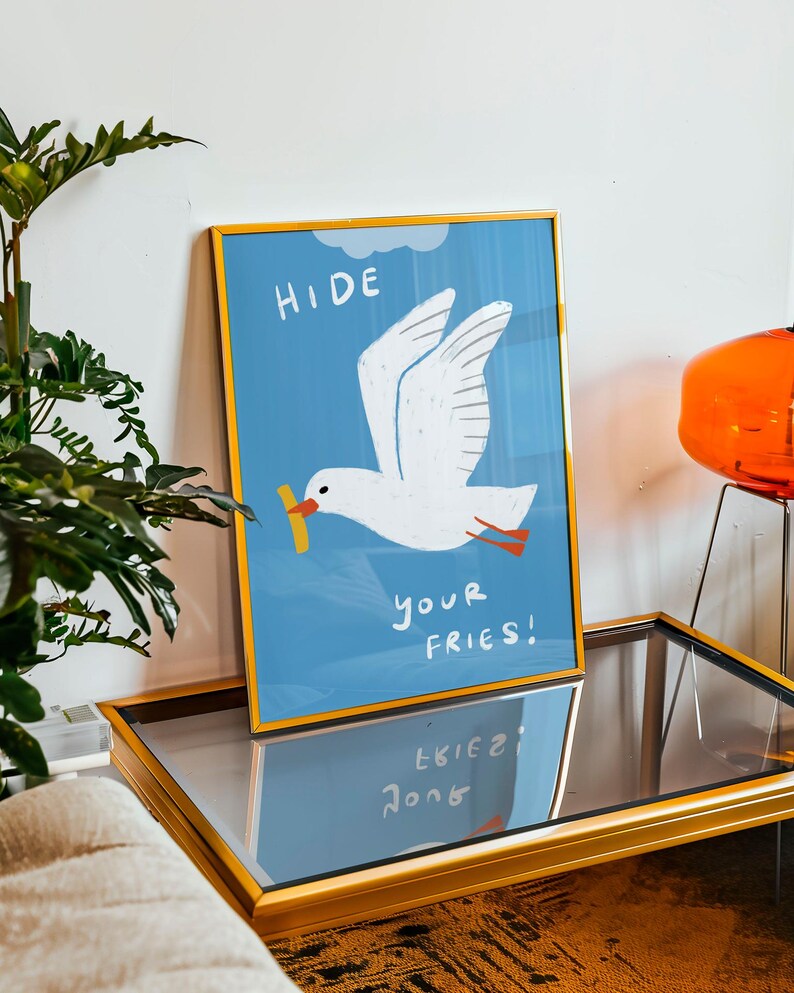 A cheeky seagull eyes a pile of fries in this vibrant, maximalist illustration, bursting with bold colors and playful text warning to protect your snacks. Perfect for adding a humorous coastal vibe to kitchens, beach house nooks, or sunny living spaces. Quirky vacation art, funny home accent, dopamine decor gift, coastal wall hanging, playful beachy print. Ideal for fry-loving friends or anyone craving a lighthearted, maximalist touch to their decor. Frame it for a pop of joy in any room.