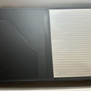 May include: A black leather folder with a lined notepad inside. The folder has a silver trim and the IBM logo with the text "Internal Telecommunications Order Executive Program".