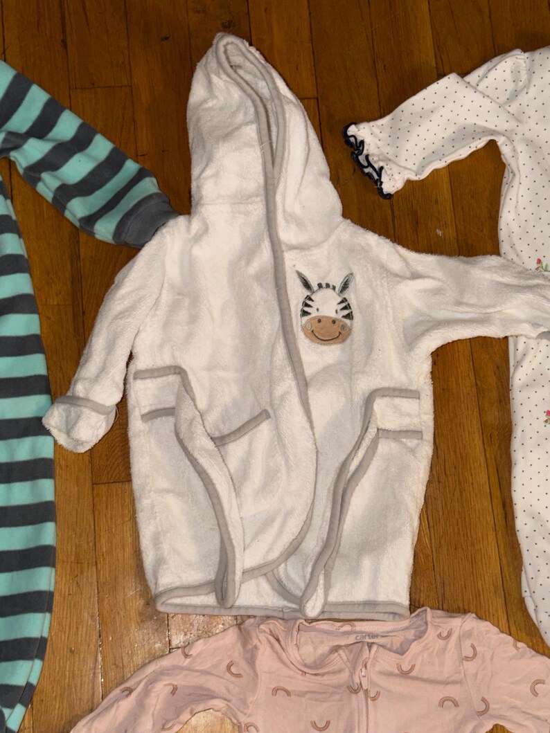 May include: A white ceramic mug with a black handle and the text "But First, Coffee" in a black, bold font. The mug is sitting on a white surface. The mug is approximately 4 inches tall.