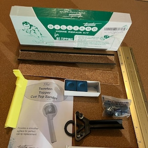 以下が含まれることがあります： ビリヤード修理用のツールとアクセサリーのコレクション。 「Billiard Home Repair Kit for Re-Tipping」と書かれた箱、キューチョーク、キューのトップサンダー、キューチップのパッケージが含まれています。 また、「Ten Minute Cement」も含まれています。