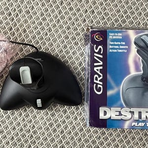 Puede incluir: Un joystick de PC Gravis Destroyer negro con un ratón a juego y una caja. La caja tiene el texto "DESTROYER PLAY TO WIN!" y "PC JOYSTICK". El joystick tiene dos botones de disparo rápido y un acelerador de acción suave.