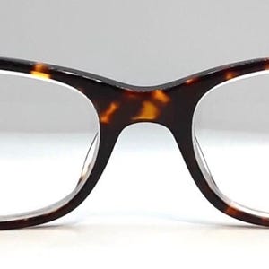 May include: A pair of eyeglasses with a tortoiseshell pattern on the frames. The frames have a cat-eye shape with a dark brown color on the temples and a lighter brown and yellow pattern on the front. The lenses are clear.