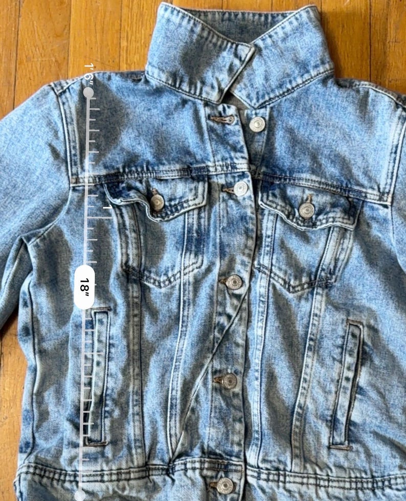 May include: Light blue denim jacket with a classic collar, button-down front, and multiple pockets. The jacket is approximately 45.7 cm long. The denim has a faded, worn look.