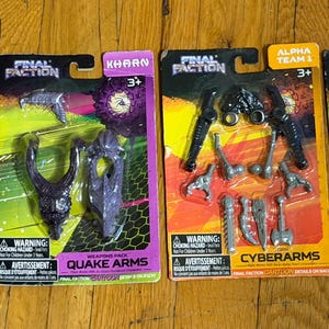 Peut inclure: Quatre packs de figurines Final Faction sur une surface en bois. Les packs présentent divers personnages et ensembles d'armes, dont "Brute", "Quake Arms", "Cyberarms" et "Striker". Chaque pack a une étiquette d'avertissement et le logo "KHARN".