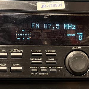 Puede incluir: Receptor de control de audio/vídeo JVC RX-777V negro. La pantalla muestra "FM 87,5 MHz". Incluye un mando de volumen maestro, selector de fuente y varias opciones de entrada. Incluye sonido envolvente Dolby Digital y DTS.