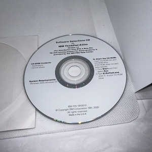 以下が含まれることがあります： 白いラベルが付いた銀色のCD-ROMディスク。ラベルには、「Software Selections CD for IBM ThinkPad A20m Version 1.0 (For Distribution Only With A New PC) Up and running support for these products is provided by the IBM PSG Help Center.」というテキストが記載されています。ラベルには、「CD-ROM Contents: Applications Device drivers System Requirements: Windows 2000, Windows NT To Start the CD-ROM: Insert CD-ROM into your CD-ROM drive CD-ROM does not start automatically 1. Click Start and then select Run 2. Type EnSoftsel.exe when E: is your CD-ROM Drive IBM P/N 19K9013 ©Copyright IBM Corporation 1981, 2000 All rights reserved Made in the U.S.A.」というテキストも記載されています。