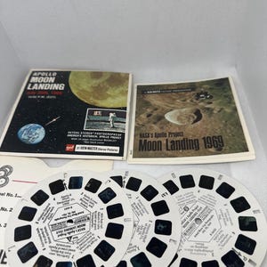 Könnte beinhalten: Ein Satz von vier View-Master-Rollen mit Bildern von der Mondlandung von Apollo 11. Die Rollen sind weiß mit schwarzem Text und Bildern. Der Text auf den Rollen lautet "NASA's Apollo Project Moon Landing 1969".