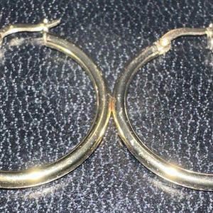 May include: A pair of gold hoop earrings. The earrings are simple and classic, with a smooth, polished finish.