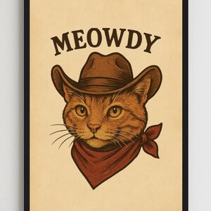 May include: Framed art print featuring a brown tabby cat wearing a cowboy hat and a red bandana. The text "MEOWDY" is printed above the cat's head in a western-style font. The artwork has a vintage, illustrated style.