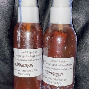 May include: Two brown glass bottles with white spray tops and labels. The labels read "Love & Light from MoonLight Healing & Crafts" and "Cinnamon Honey, Abundance and Prosperity".