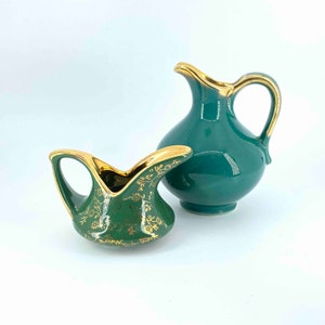 Puede incluir: Dos jarras de cer&aacute;mica verde con detalles dorados. La jarra m&aacute;s peque&ntilde;a tiene un dise&ntilde;o floral decorativo. La jarra m&aacute;s grande tiene un dise&ntilde;o simple.