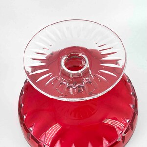 Puede incluir: Un pedestal de vidrio transparente con un taz&oacute;n de vidrio rojo. El pedestal tiene un dise&ntilde;o decorativo de vidrio cortado. El taz&oacute;n tiene un borde festoneado.