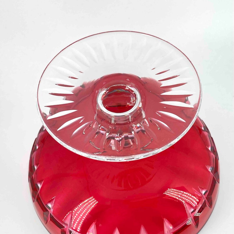 Puede incluir: Un pedestal de vidrio transparente con un taz&oacute;n de vidrio rojo. El pedestal tiene un dise&ntilde;o decorativo de vidrio cortado. El taz&oacute;n tiene un borde festoneado.