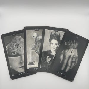 May include: Four tarot cards with black borders and grayscale illustrations. The cards feature surreal imagery, including a face with multiple eyes, a figure pouring liquid into a cup, a woman with a crown, and a hand wearing a crown.