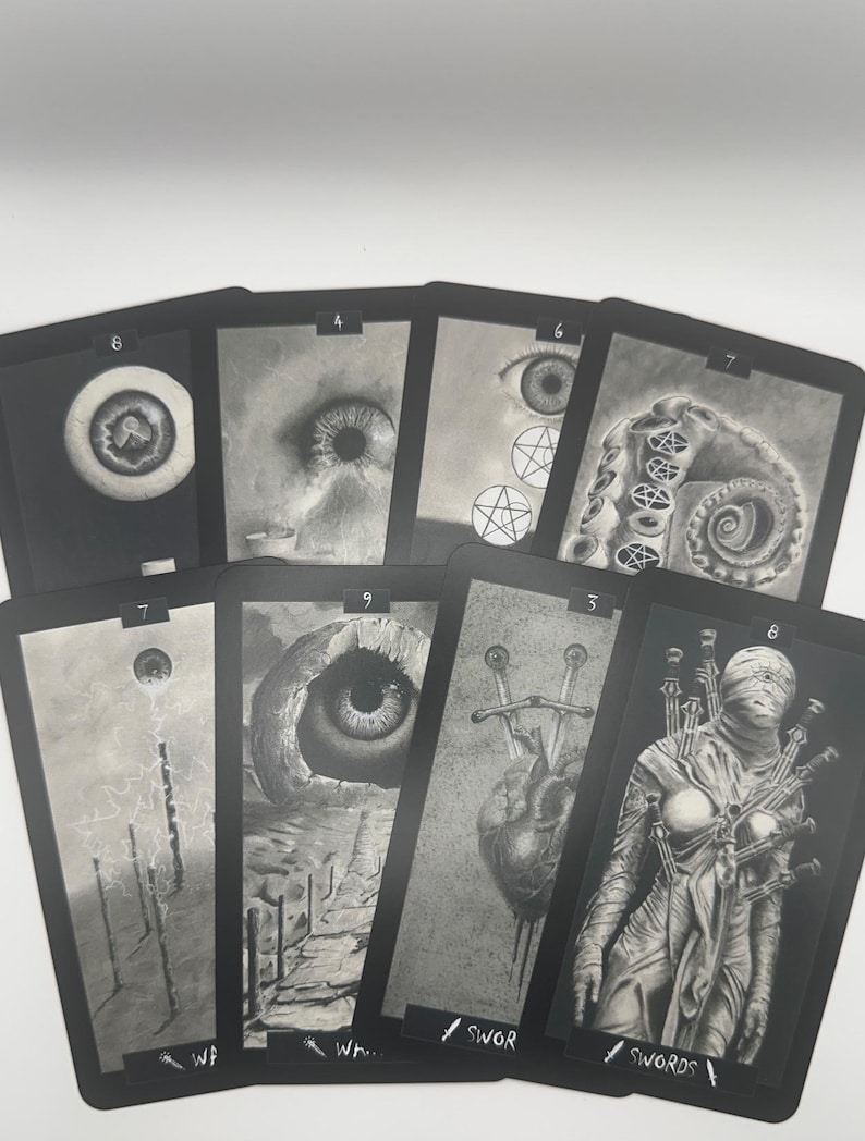 May include: A collection of tarot cards with dark, grayscale illustrations. Each card features a unique, detailed drawing, including eyes, tentacles, and figures, with titles like "Swords" and numbers at the top.