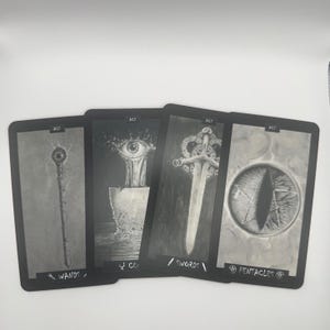 May include: Four tarot cards with black borders and grayscale illustrations. The cards feature images of a wand, an eye, a sword, and an eye within a star. The word "ACE" is at the top of each card.