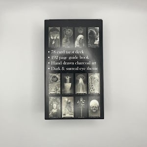 May include: A black tarot card box with a dark and surreal eye theme. The box features hand-drawn charcoal art and includes a 78-card tarot deck and a 192-page guide book. The box has a series of black and white images.