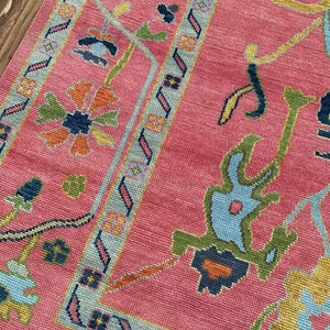 Handmade oriental pink rug with multicolor flowers and vines.