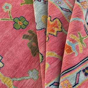 Vibrant pink area rug with colorful floral motifs and geometric border.